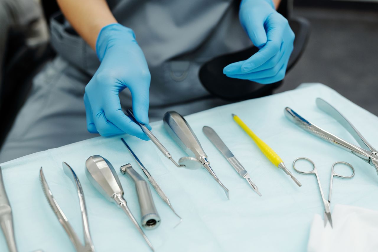 Close-up of gloved hands organizing dental tools in a clinical setting.